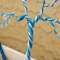 swirl of blue and silver color wire are wrapped around each other to form the treee trunk the tree trunk splits of into 2 directions 